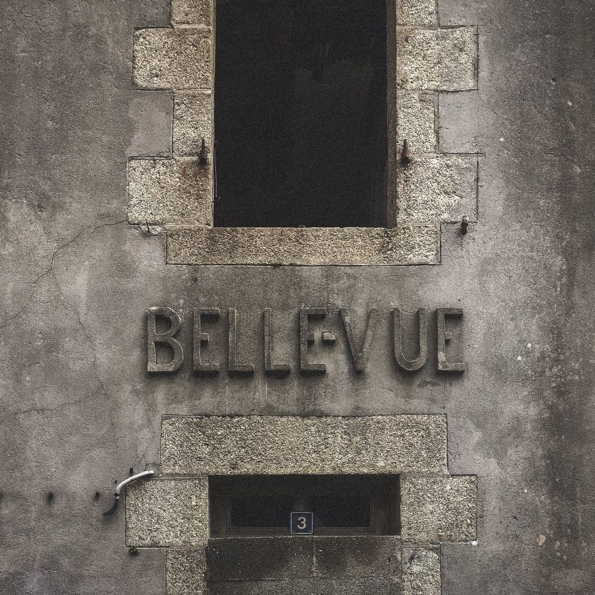 Façade en pierre d’un ancien bâtiment à Roscanvel, avec l’inscription « Bellevue » gravée dans le mur