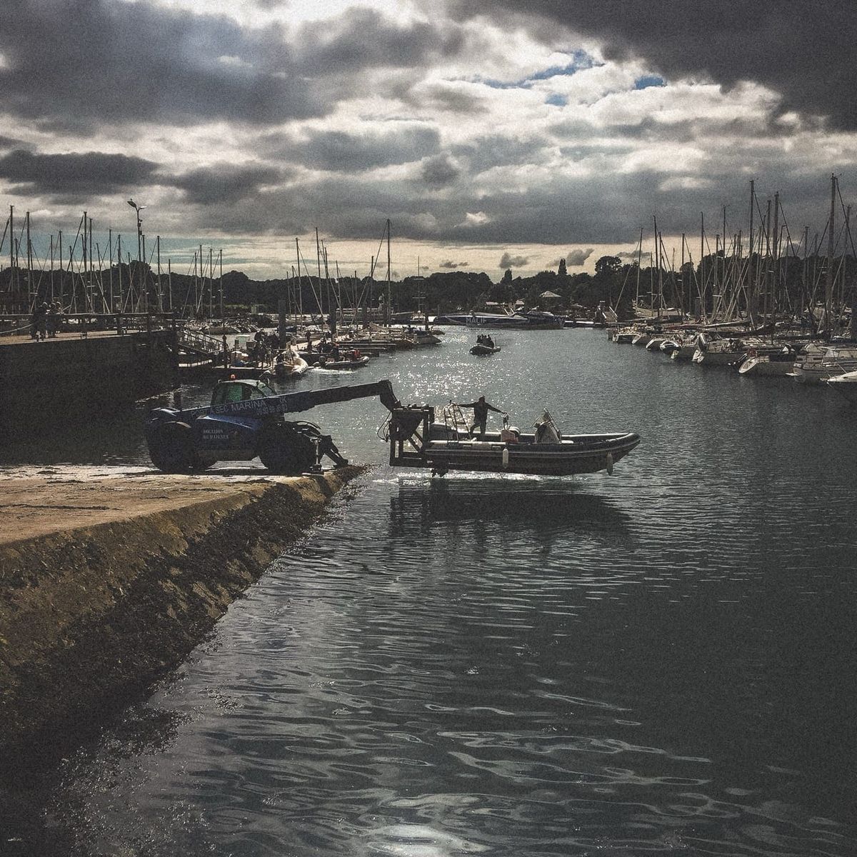 Zodiac suspendu à une grue au-dessus de l’eau sur le port de Fouesnant en Bretagne
