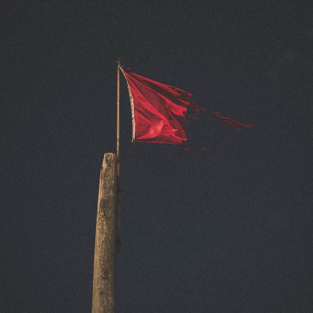 Drapeau rouge déchiré par le vent sur la plage de Sainte-Anne-la-Palud dans le Finistère
