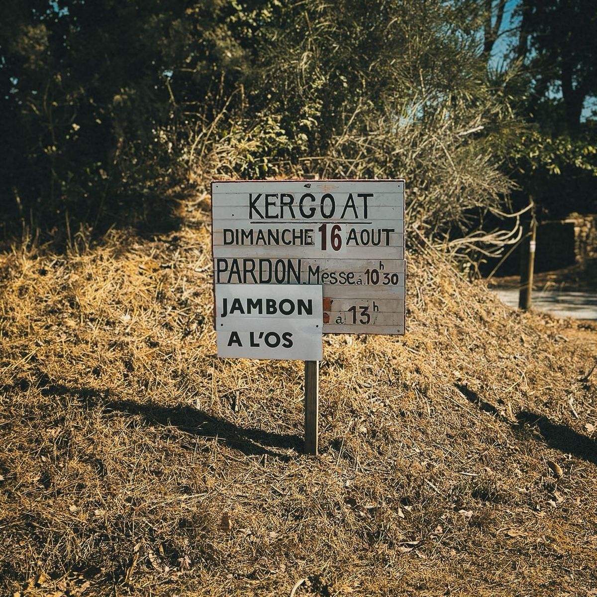 Pancarte annonçant le pardon de Kergoat et un jambon à l’os, à la sortie d’un parking de Locronan.