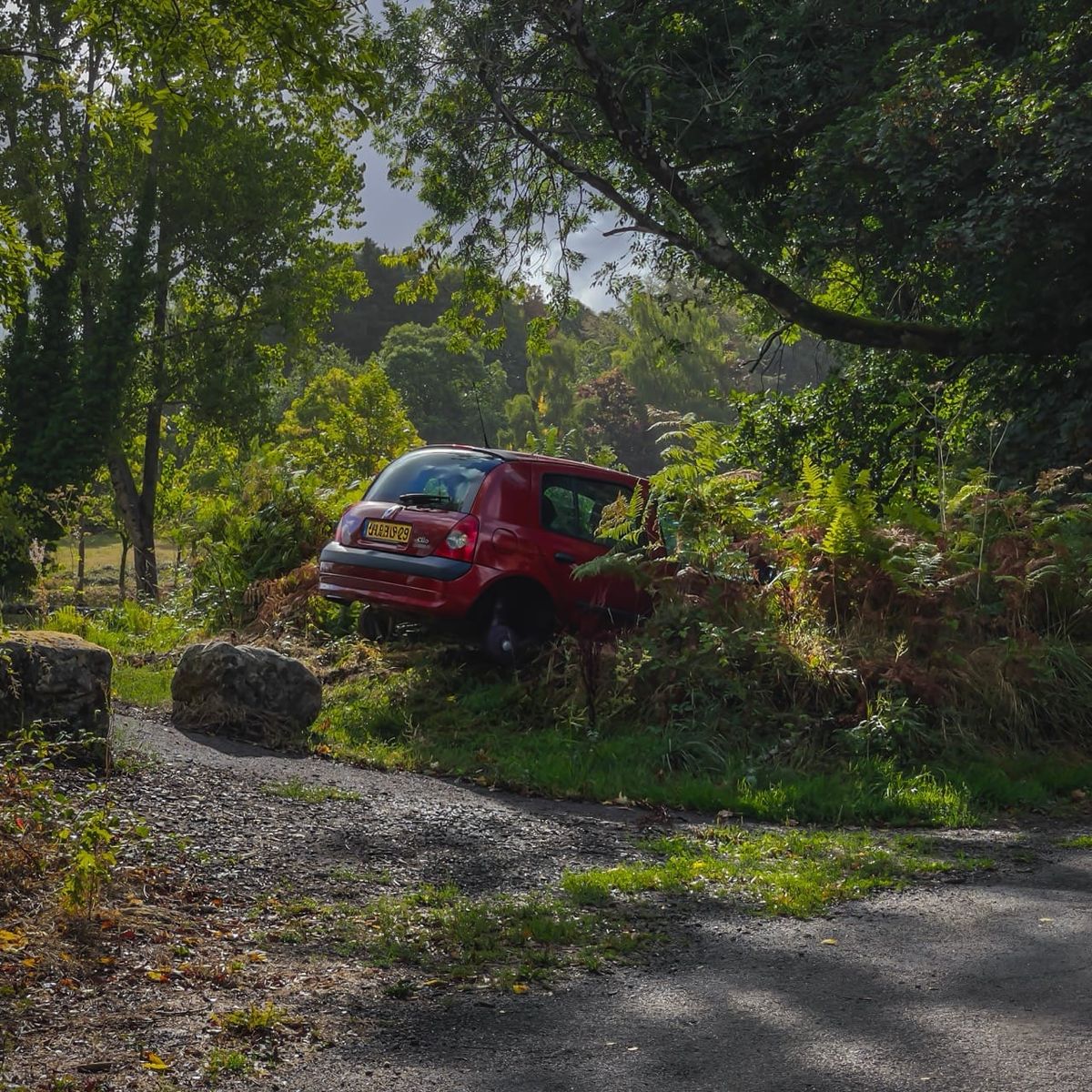 Clio rouge sans roues dans la végétation à Quimper, Finistère