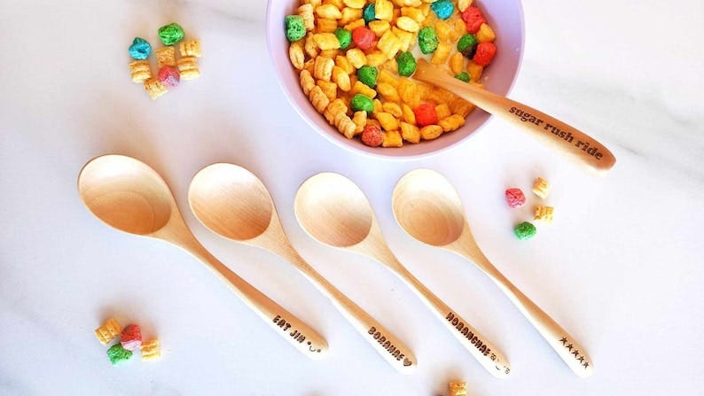 A picture of bowl of soup with a wooden spoon in it. Other wooden spoons also are on display, with words such as "Eat Jin" or "Borahae" on their handles.