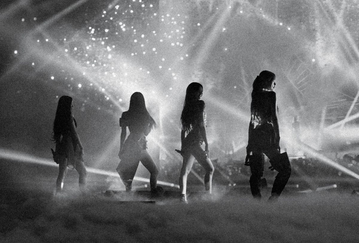 A black and white photo of BLACKPINK on stage, with all four women in silhouette