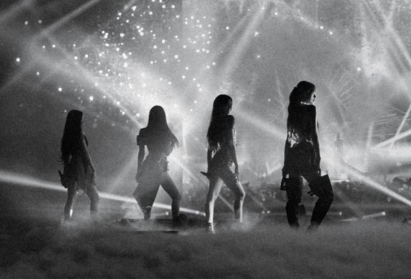A black and white photo of BLACKPINK on stage, with all four women in silhouette