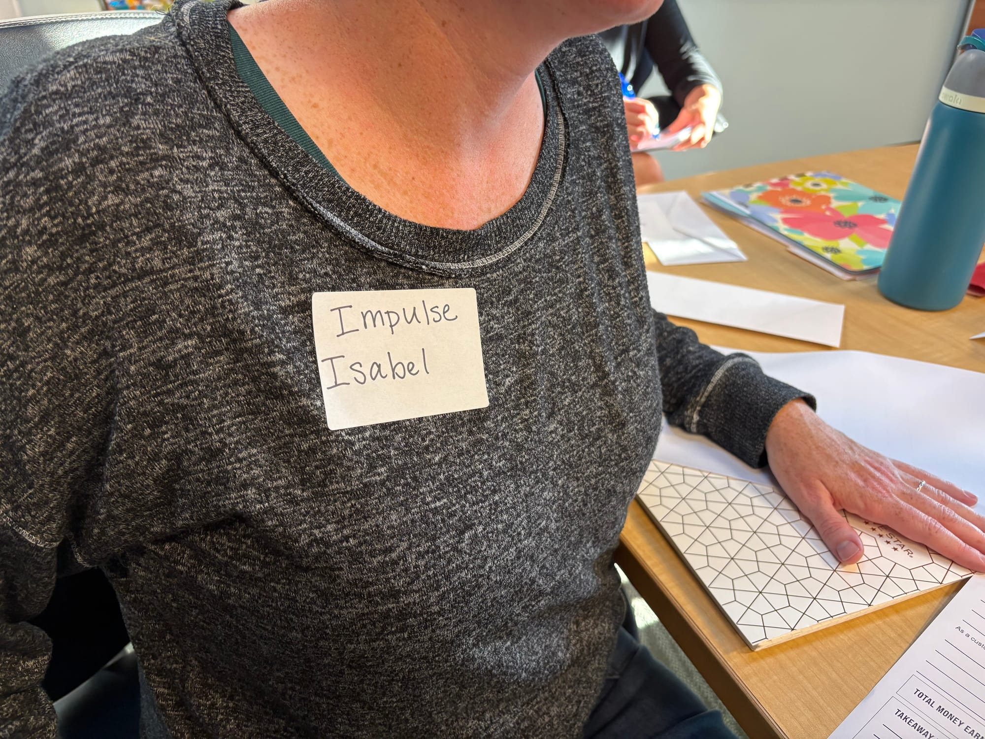 A close-up of a name tag on a person's shirt. It reads Impulse Isabel