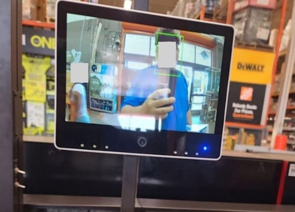 A photo of a checkout screen showing a person taking a photo of himself, with a green box around his face, indicating likely use of facial recognition.