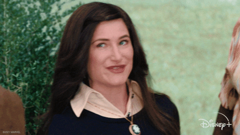 an animated GIF of Kathryn Hahn in Parks and Recreation, giving an overly cheeky wink as if to say, "this isn't actually what's happening."