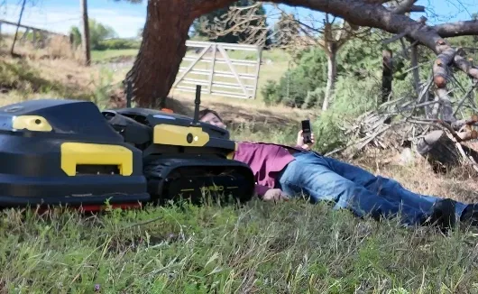 an animated GIF of an outdoor patch of grass, and a robot lawnmower running over journalist Sean Hollister who's laying down in front of it.