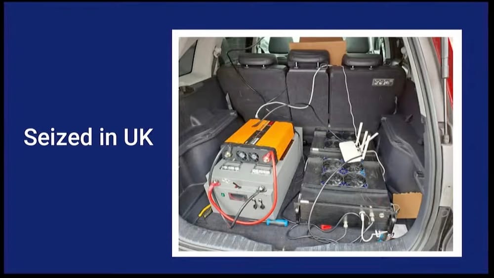 a slide from a Toronto Police presentation, saying "Seized in UK," with an image of an SMS blaster equipment, with wires and exhaust fans, in the back of a car.