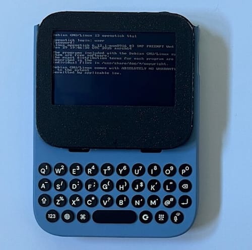 a photo of a Clicks Communicator (a magnetic handheld phone keyboard) with a $20 4G hotspot with a LED display screen containing a bunch of text showing Linux's bootloader messages.