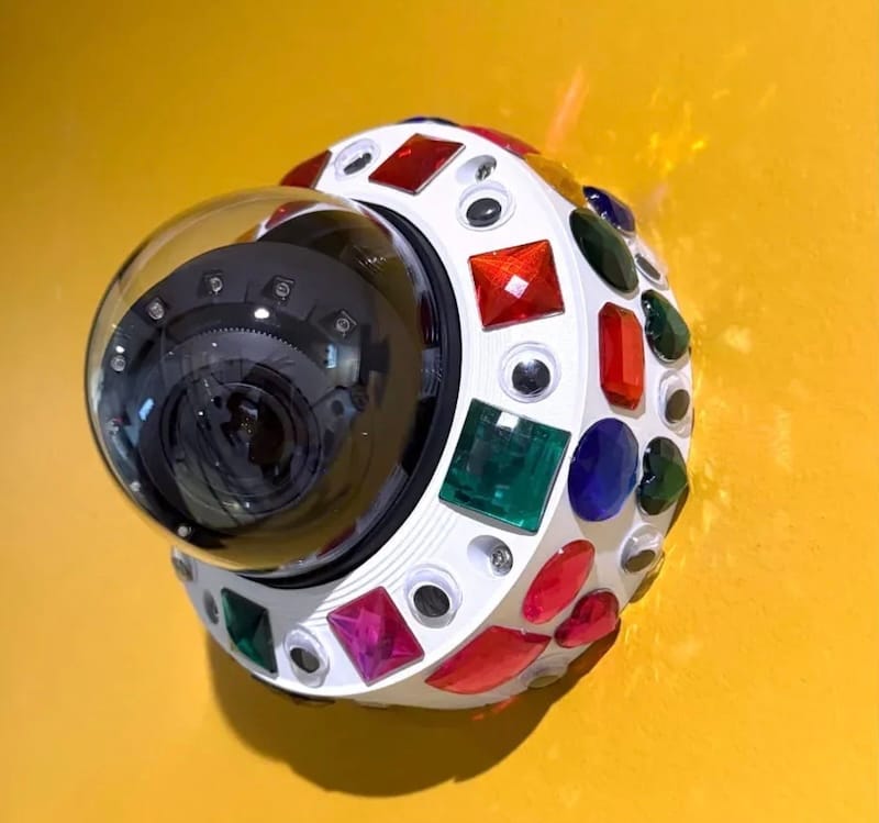 a photo of a bedazzled CCTV camera, covered in stick-on jewels, to make it stand out and look far more obvious that it's a surveillance camera.