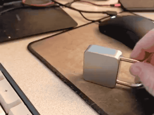 A smart padlock being hit on its side, forcing the lock to pop open. 