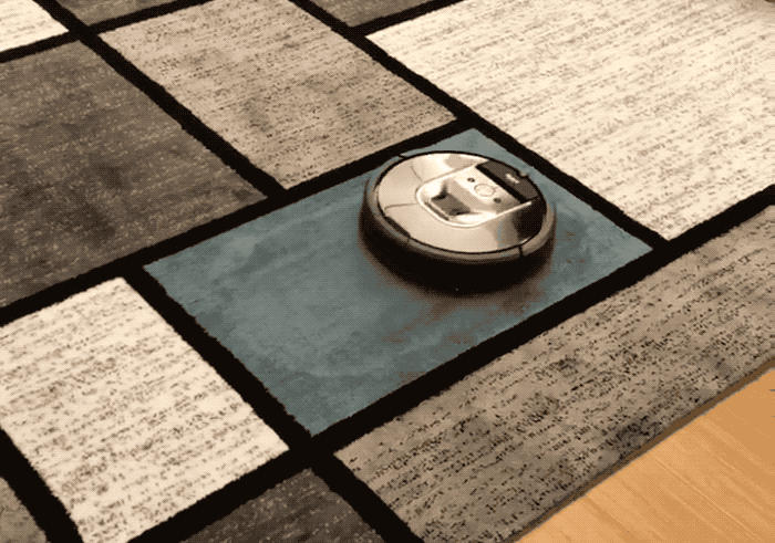 A Roomba robot getting stuck on a square-patterned rug.
