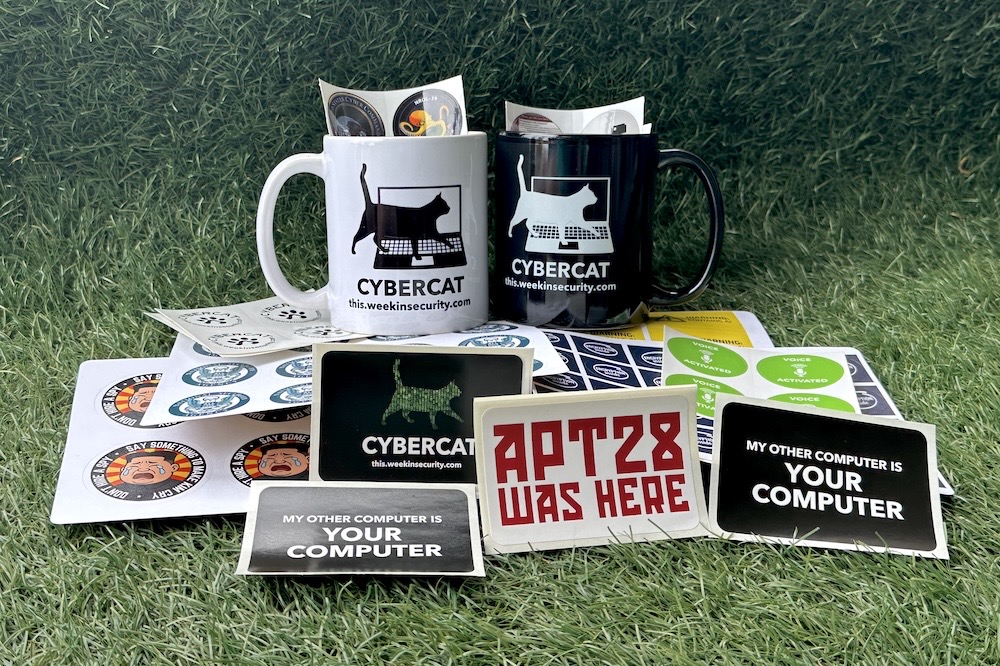 A selection of ~this week in security~ swag, including a "Cybercat" themed mugs (in both black and white) and a bunch of custom cybersecurity-themed stickers on a grassy background