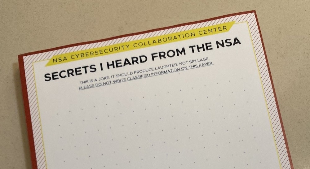 A notepad of paper titled, "NSA CYBERSECURITY COLLABORATION CENTER" with the subheading, "SECRETS I HEARD FROM THE NSA." The next line reads: "THIS IS A JOKE. IT SHOULD PRODUCE LAUGHTER, NOT SPILLAGE. PLEASE DO NOT WRITE CLASSIFIED INFORMATION ON THIS PAPER."