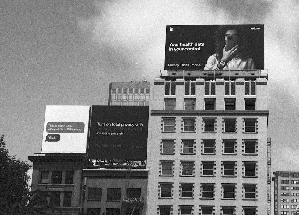 A beautiful monochrome photo of two privacy-remarking billboards on top of buildings, one by Apple and one by WhatsApp.