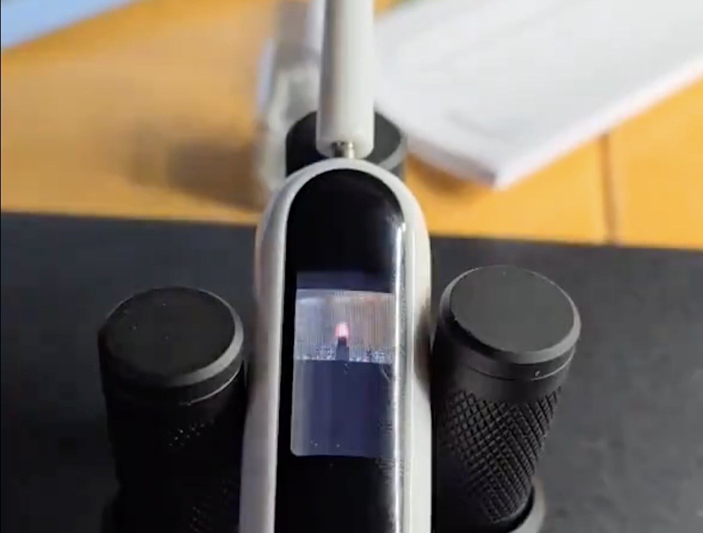 A photo of Doom running in a tiny LCD display on a toothbrush, held in place on a test lab bench.