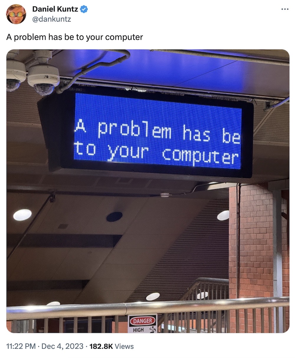 Dan Kuntz tweet: "A problem has be to your computer," followed by a photo of a NYC subway sign with a zoomed-in blue-screen-of-death, which reads "A problem has be to your computer"