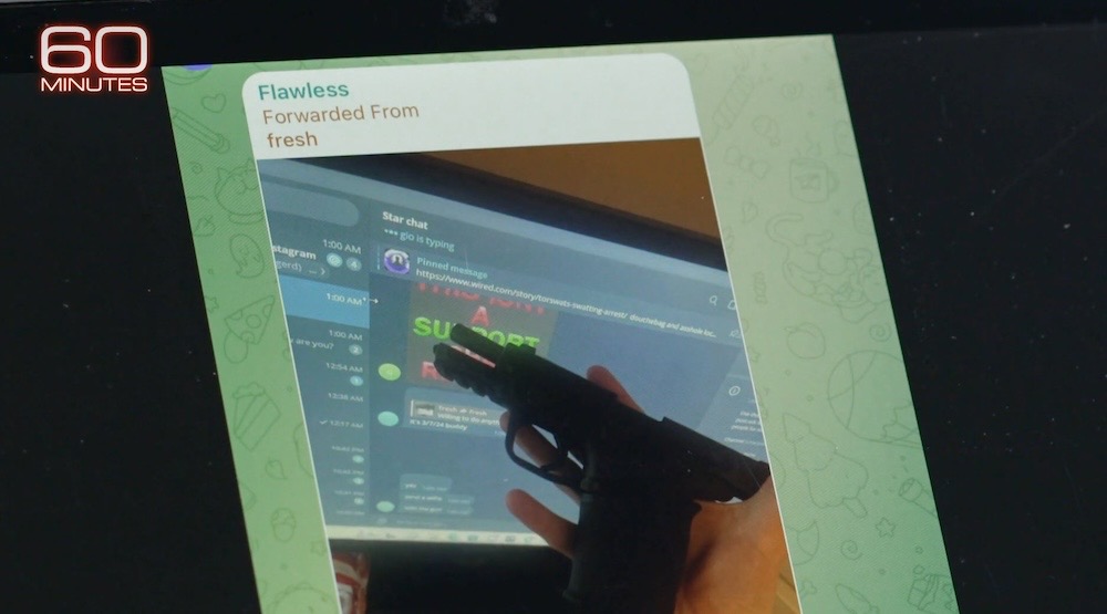 A screenshot of the 60 Minutes report showing a member of the Com subculture threatening someone with a weapon, a pistol, held over a Telegram chat of another hacker.