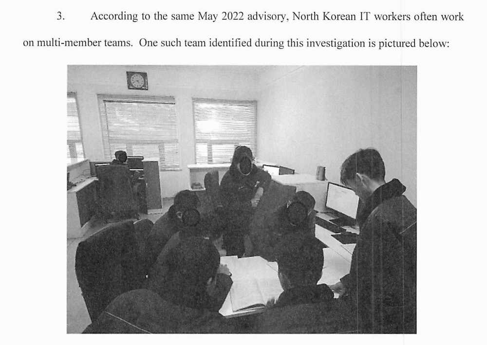 A screenshot from the DOJ indictment, which reads: "According to the same May 2022 advisory, North Korean IT workers often work on multi-member teams. One such team identified during this investigation is pictured below:" followed by a photo of several North Koreans working from an office, albeit with their faces redacted.