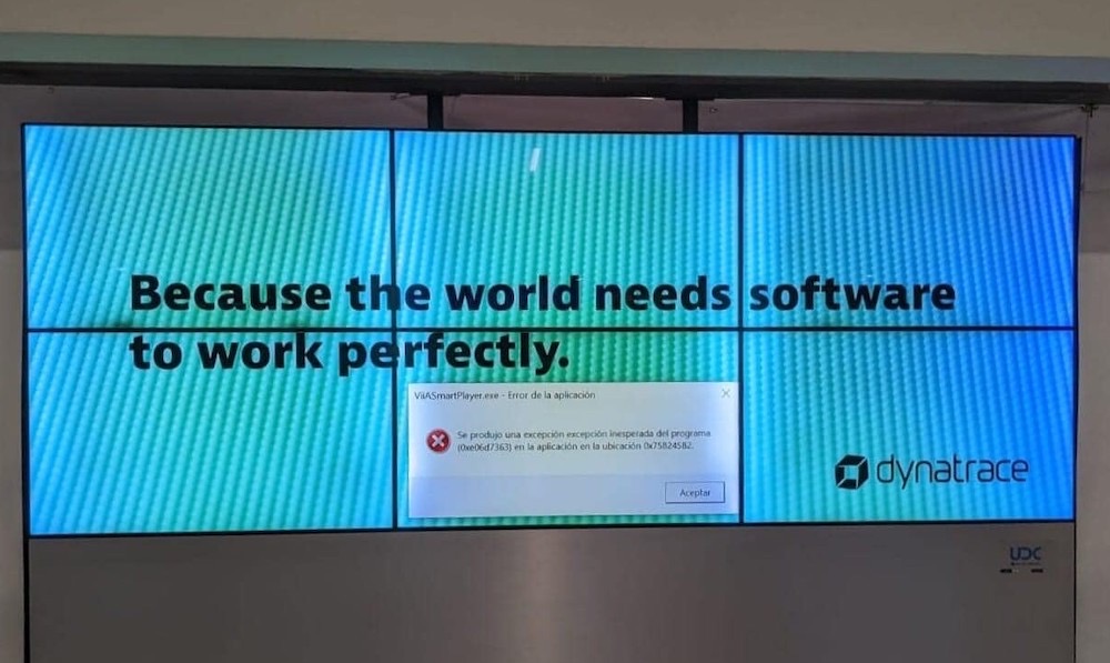 A large digital billboard that says, "Because the world needs software to work perfectly" that includes a Windows error prompt.