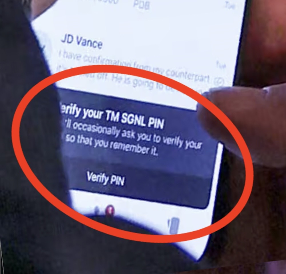 A photo from the White House cabinet room, which shows Michael Waltz using his phone, with a knock-off version of Signal on the screen,