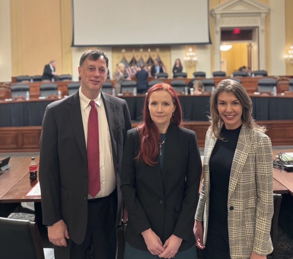 A photo of Rob Joyce (former NSA cyber director), then Emma M. Stewart (Idaho National Lab) and Laura Galante (former Office of the DNI) pose for a photo in front of the House chamber for the Committee on the CCP that they're about to testify to. 