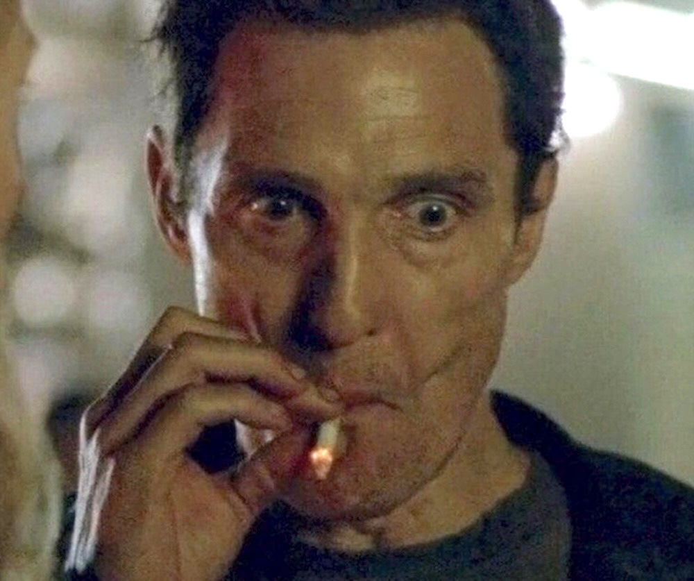 A photo of a meme of Matthew McConaughey in character, with an alarmed/panicked look on his face, taking a heavy drag from a lit cigarette.