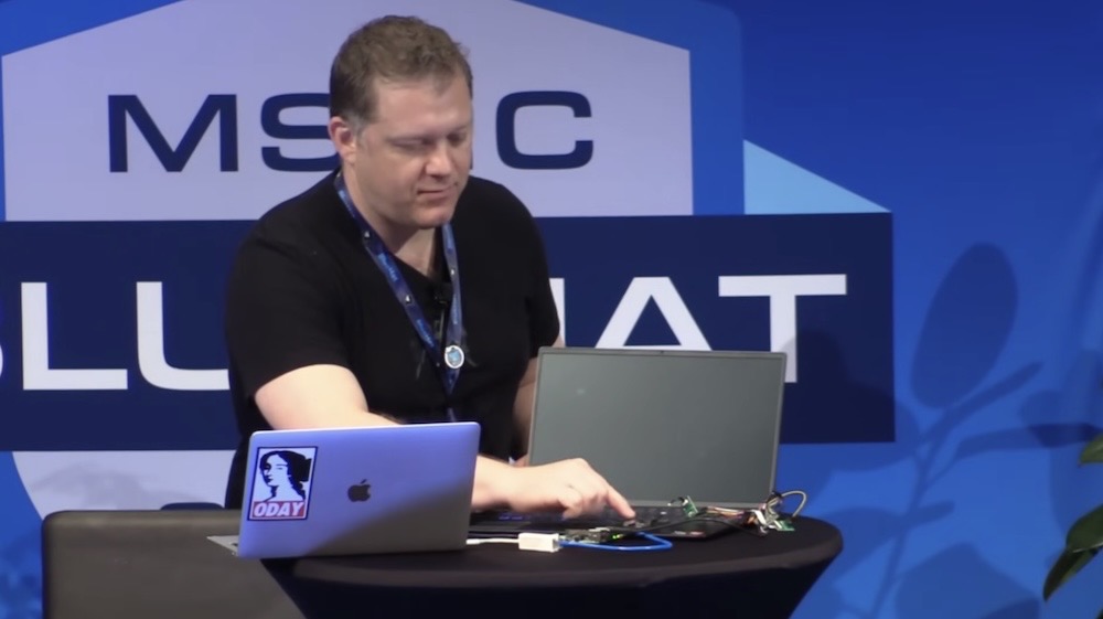 A screenshot showing a security researcher demonstrating an exploit to bypass Windows Hello on stage at Microsoft's Blue Hat conference.