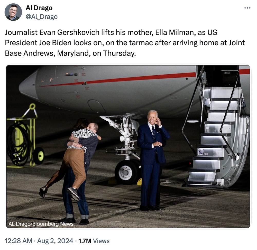 Al Drago tweet: "Journalist Evan Gershkovich lifts his mother, Ella Milman, as US President Joe Biden looks on, on the tarmac after arriving home at Joint Base Andrews, Maryland, on Thursday," followed by a photo of Evan picking up and hugging his mum by the plane's doors, with President Biden looking on smiling.