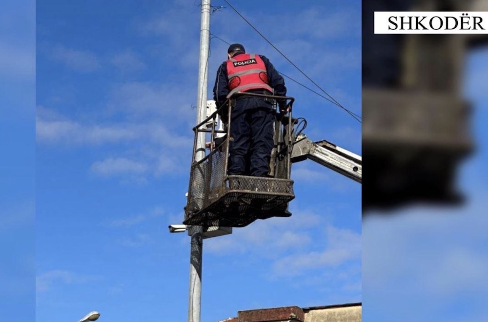 A photo of a police officer on a telescopic platform removing a criminal CCTV camera from a public light post in Tirana.