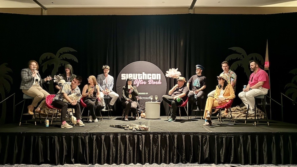 A photo of a dozen or so speakers on the stage at Sleuthcon in an inadvertent renaissance-style photo.