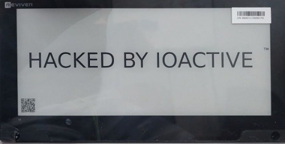 A photo of a hacked digital license plate, which reads: "HACKED BY IOACTIVE".