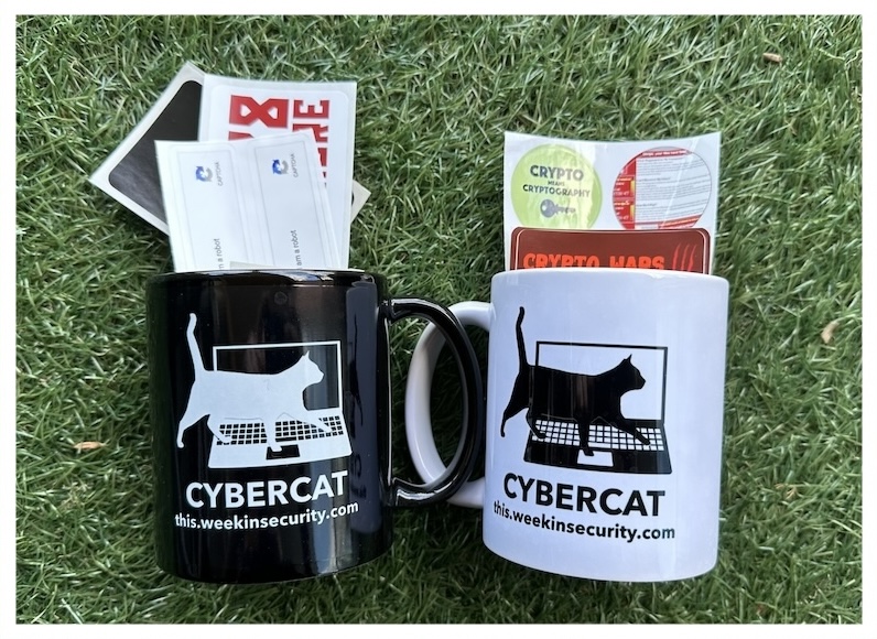 A photo of a selection of stickers and mugs featuring ~this week in security~'s cyber cat.