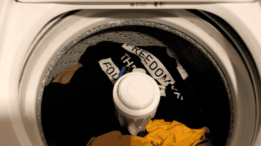 An animated GIF of a washing machine lid opening and water pouring over a set of security keys on top of some laundry.