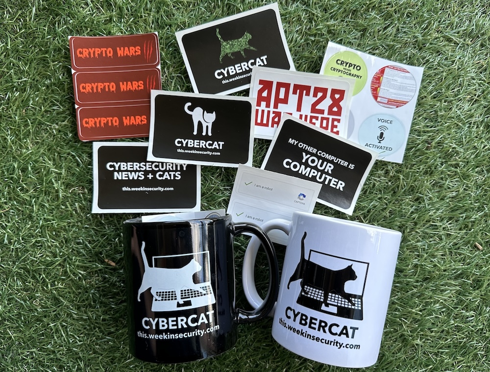 A photo of a selection of stickers and two mugs (one in black and one in white) featuring cyber cats. The stickers and mugs are laid out against a green grass background.