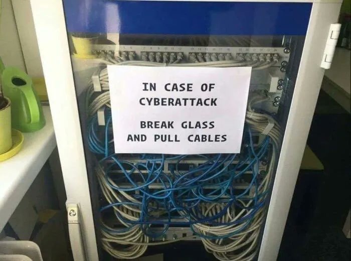 A server rack with a glass front panel with a sign saying, "In case of cyberattack, break glass and pull cables."