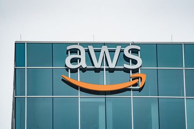 a photo showing Amazon Web Services' logo on the outside of a glass building.