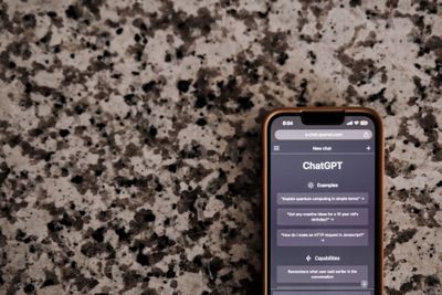 a close-up of a smartphone with ChatGPT interface on a speckled surface, highlighting technology and AI.