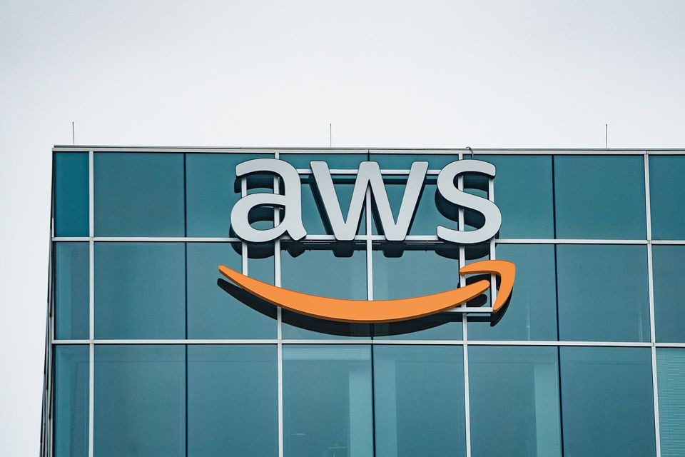 a photo showing Amazon Web Services' logo on the outside of a glass building.