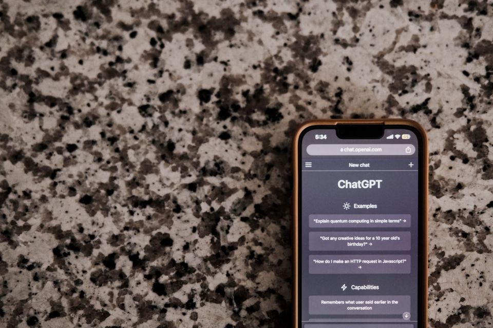 a close-up of a smartphone with ChatGPT interface on a speckled surface, highlighting technology and AI.
