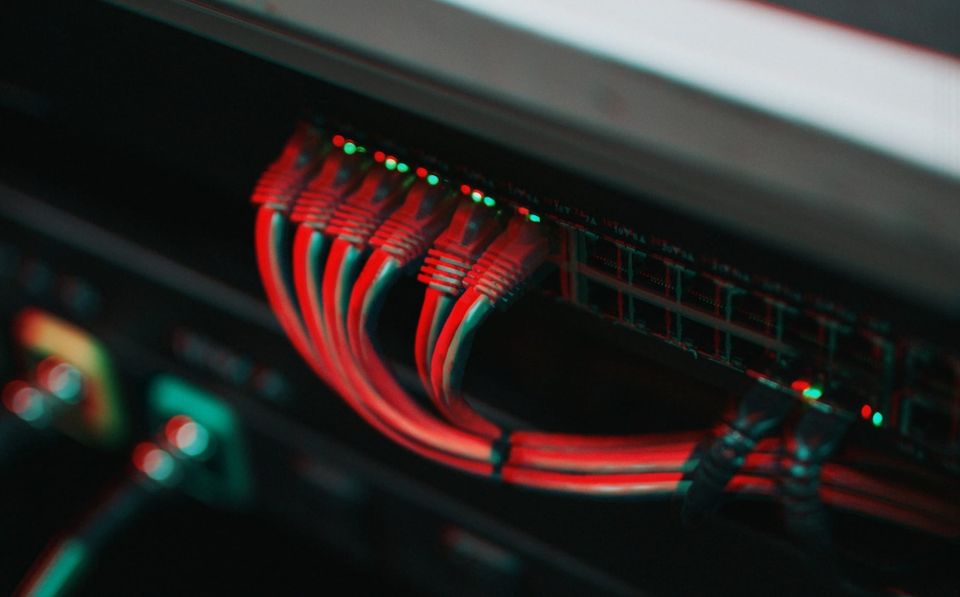 a photo of the back of a network box, featuring a bunch of red cables and flashing lights. 