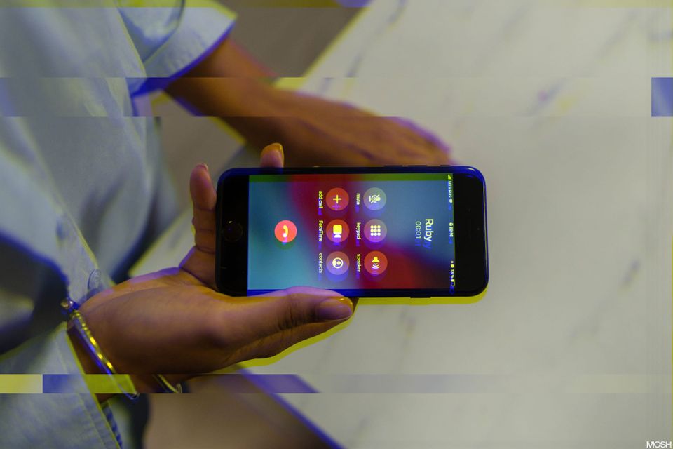 a photo looking down from the first-person perspective of a person's hands holding an iPhone taking a phone call, the caller ID says "Ruby".