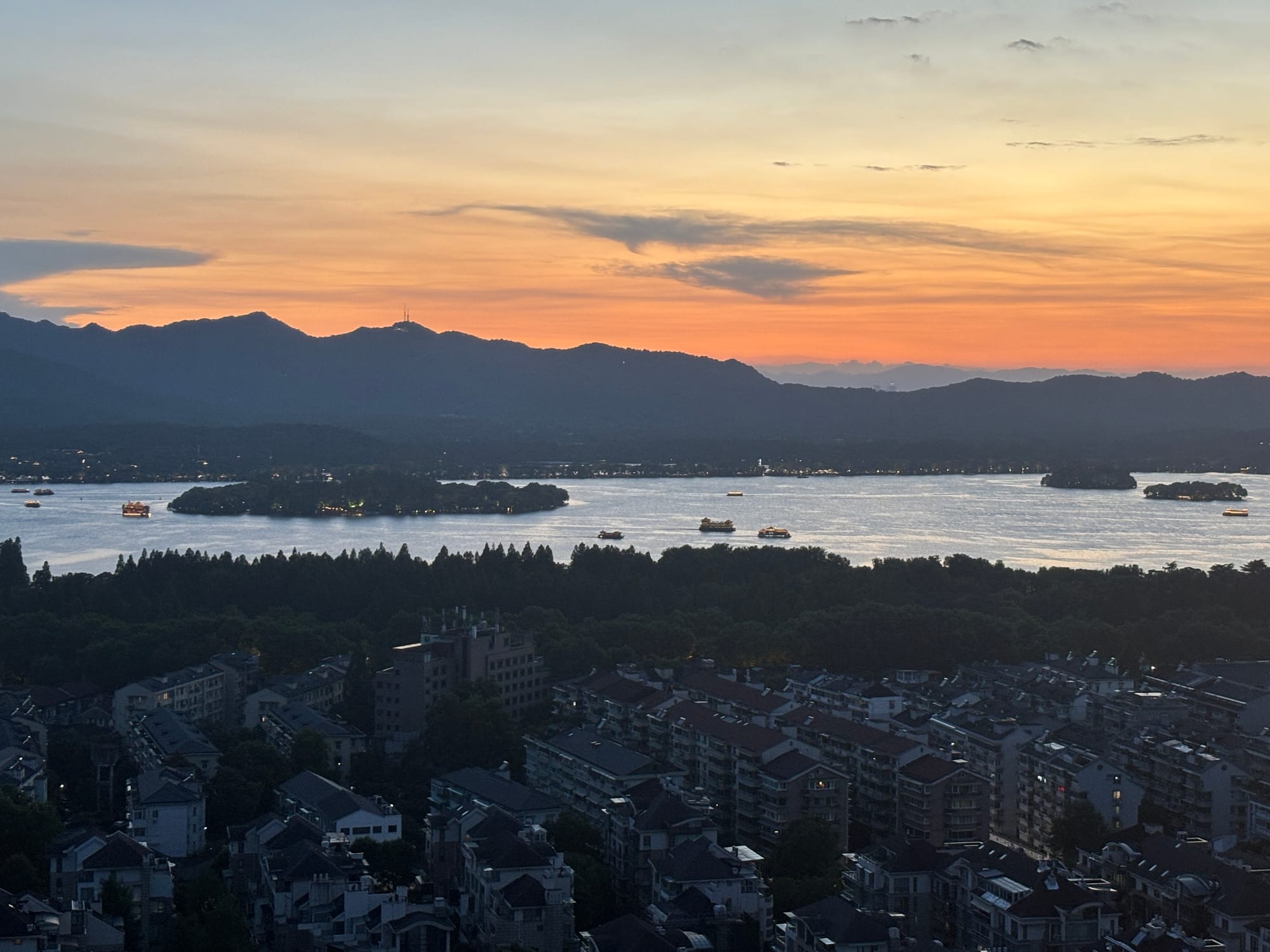 The romantic night view of West Lake and the glowing city lights of Hangzhou from City God Temple