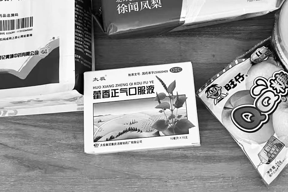 A box of HuoXiang ZhengQi Shui with small brown glass vials, a traditional Chinese medicine used as a travel hack for heatstroke, summer cold, and AC temperature shock.