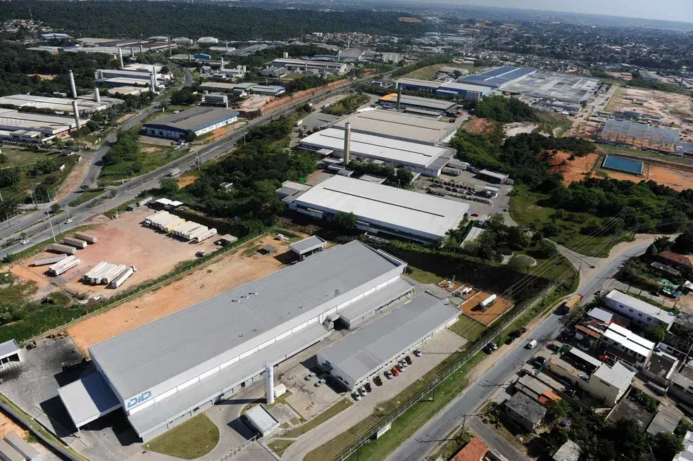 Contêineres empilhados no terminal do Super Terminais, em Manaus, com um navio ao fundo no Rio Negro