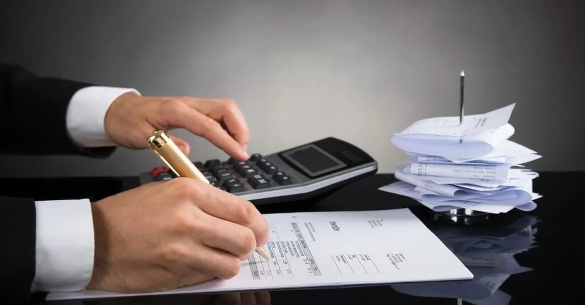 Mãos digitando em um teclado de notebook, com uma nota fiscal eletrônica (NF-e) em destaque na tela