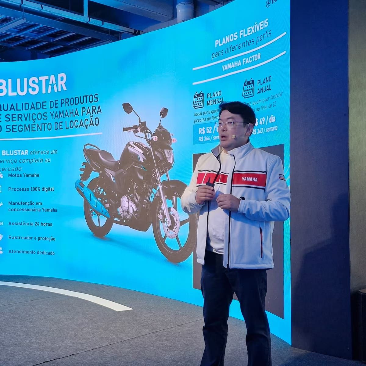 Motocicleta Yamaha Factor 150 ED branca estacionada em rua, com prédios ao fundo