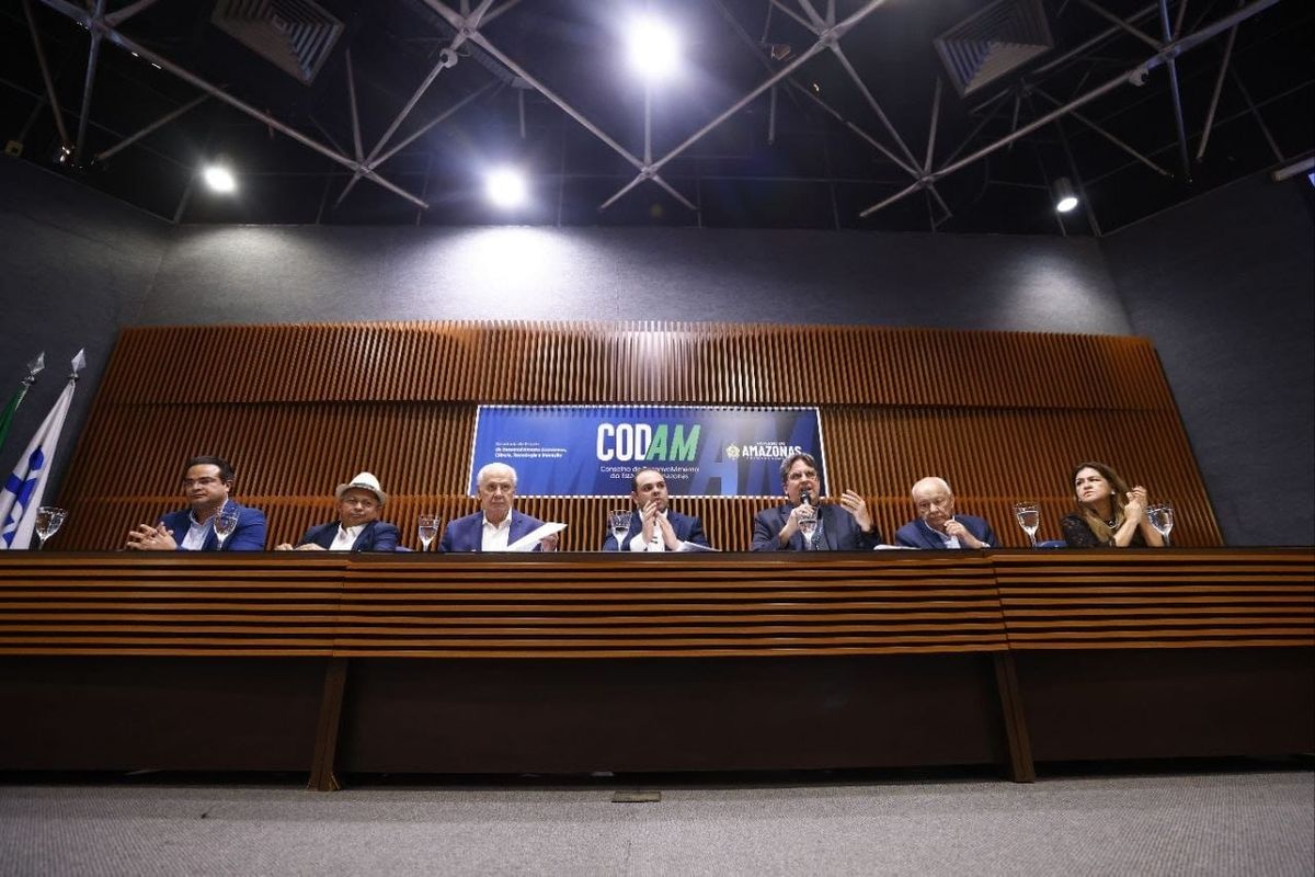 Membros do Conselho de Desenvolvimento do Estado do Amazonas (Codam) sentados em uma mesa de reunião, com um banner do Codam ao fundo