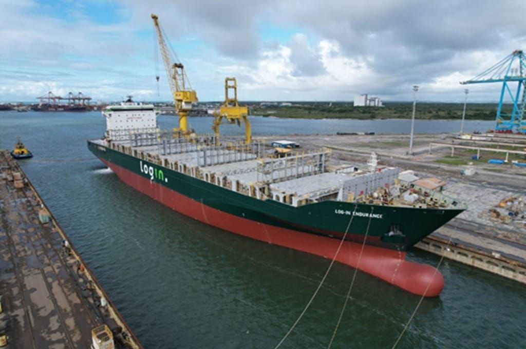 Navio porta-contêineres Log-In Endurance atracado em doca, com guindastes amarelos ao fundo e o logotipo da Log-In no casco